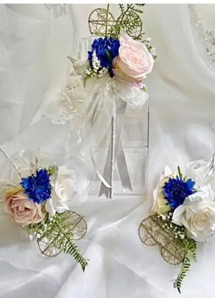 Floral corsages with blue and pink flowers on a white fabric background