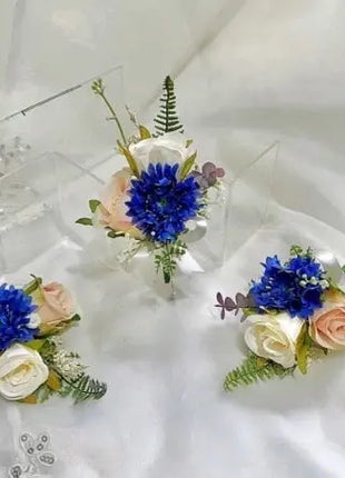 Three floral corsages with blue and white flowers on a white background