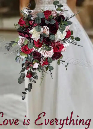 Bouquet of red, white, and green flowers held by a person wearing a white dress with 'Love is Everything' text.