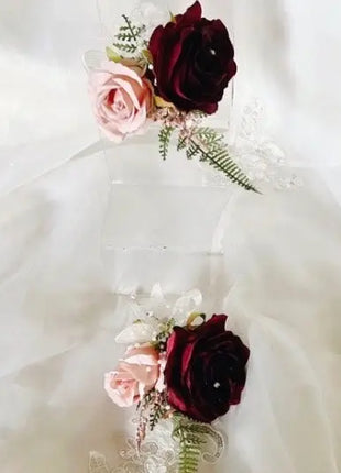 Two floral corsages with pink and red flowers on a white lace fabric background