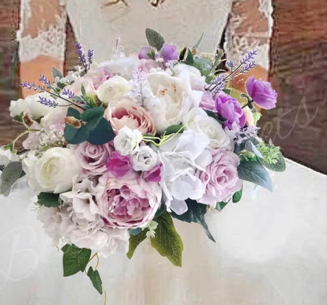 Bouquet of flowers with white, pink, and purple colors held by a person wearing a lace dress.