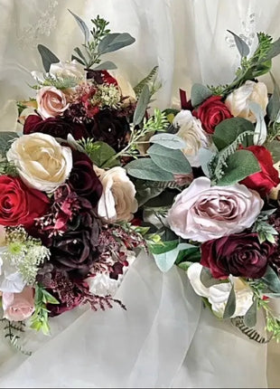 Bouquet of red, white, and burgundy roses with greenery on a white background