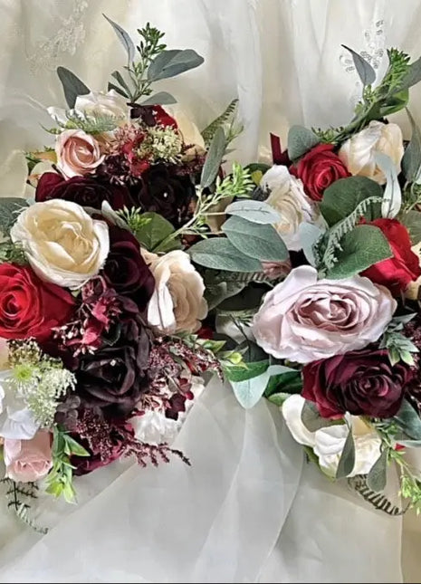 Bouquet of red, white, and burgundy roses with greenery on a white background