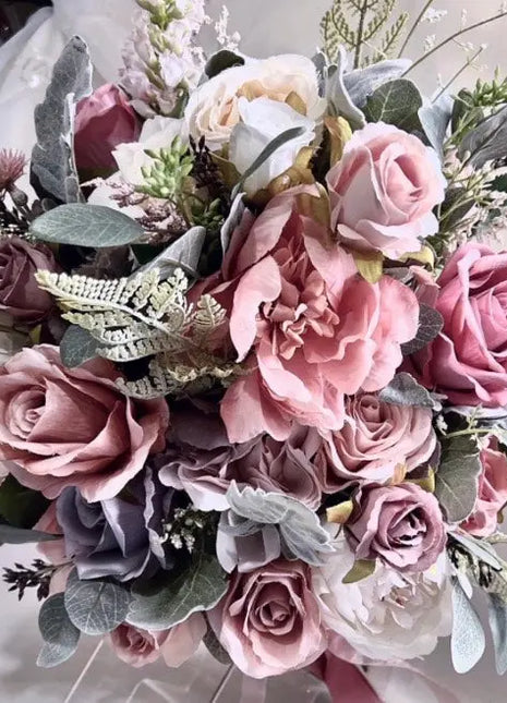 Bouquet of pink and purple flowers with greenery on a white background