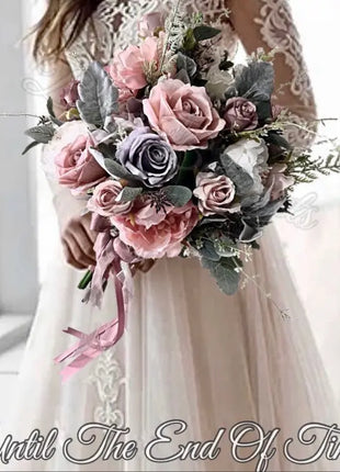 Bouquet of pink and gray flowers held by a person wearing a white lace dress.