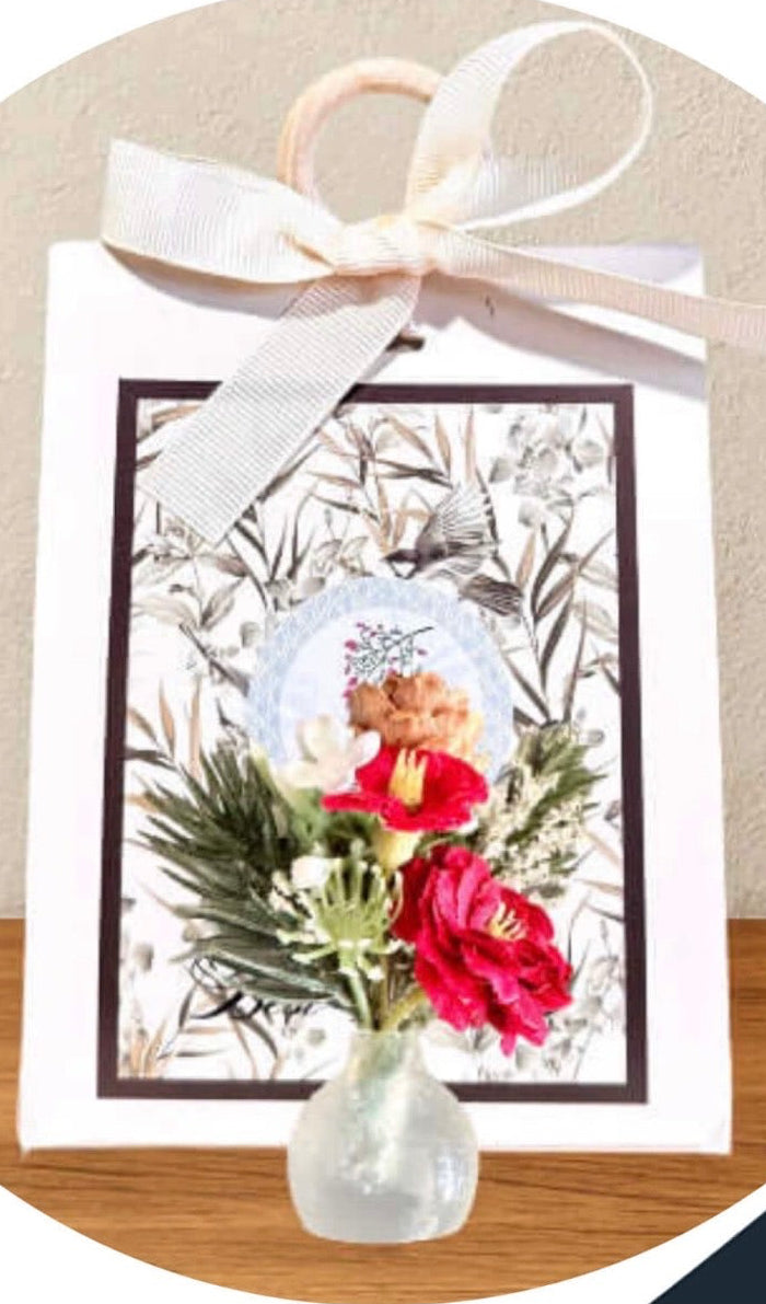 Floral arrangement in a vase with a decorative card on a wooden surface