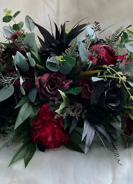 Bouquet of dark red and green flowers on a white fabric background