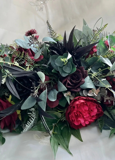 Floral silk  arrangement  in black and red on a white  fabric background with intricate details