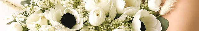 Bride holding a bouquet of white flowers with greenery