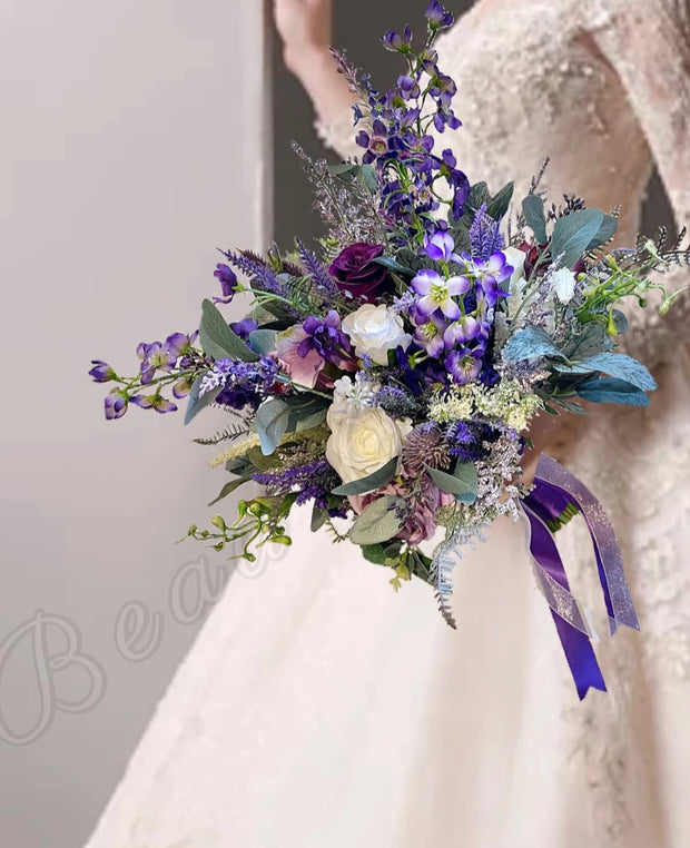 Bouquet of flowers with purple and green tones held by a person wearing a lace dress.