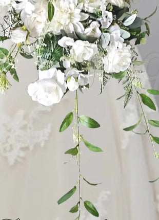 Bouquet of white flowers with green leaves held by a person wearing a white dress, with 'Fairytale' branding.