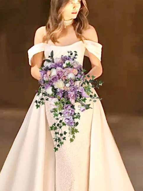Woman in a white off-shoulder dress holding a bouquet of flowers against a blurred background